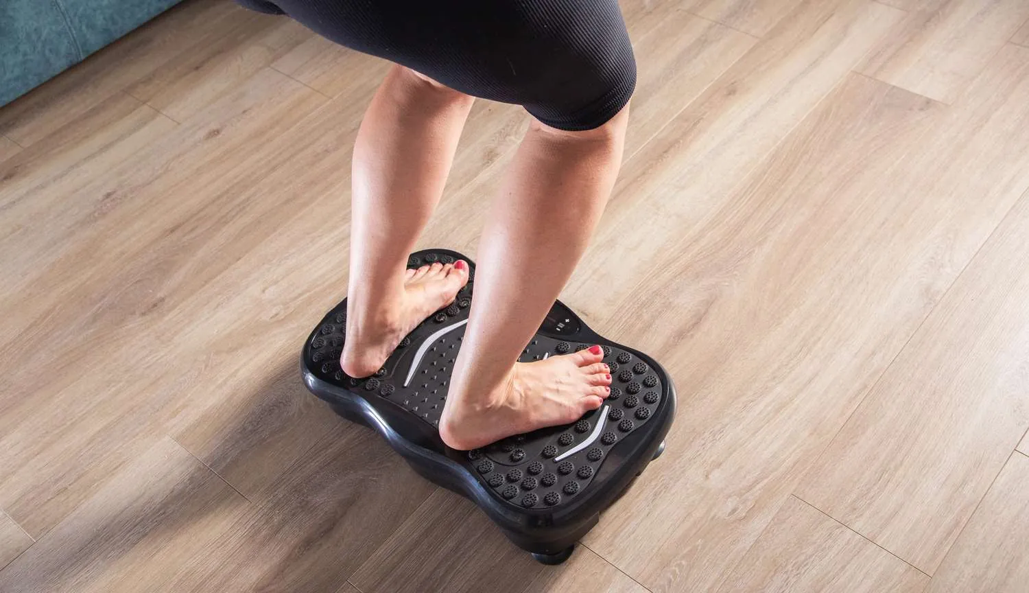 Person standing with soft knees on vibration plate during morning workout