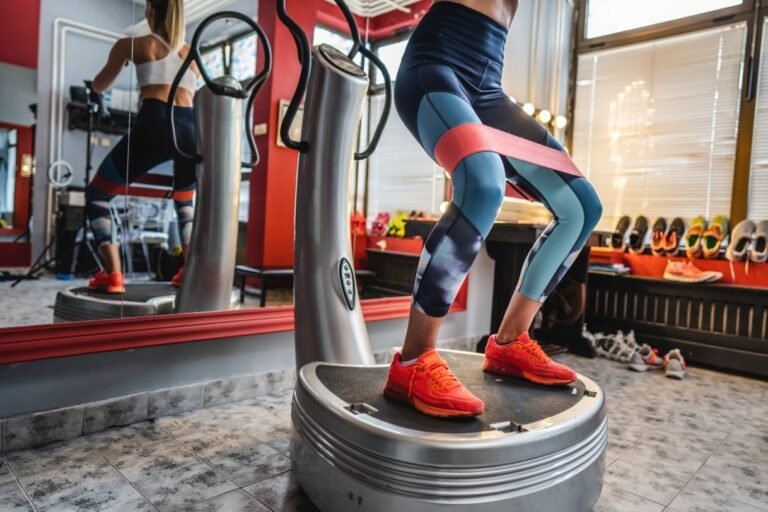 Vibration plate machine beside a yoga mat and dumbbells in a bright home room