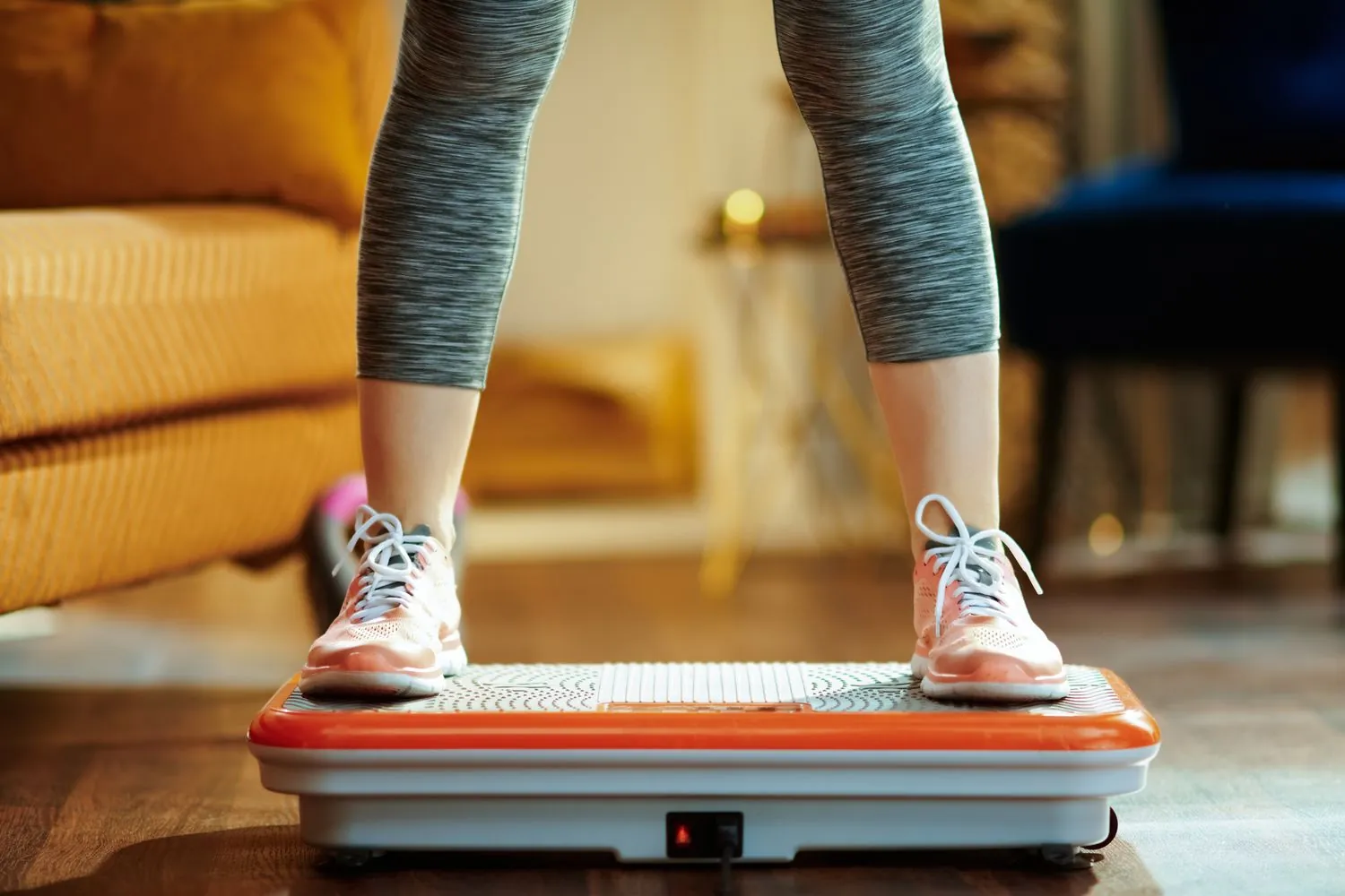 Woman doing squats on a vibration plate in a home gym